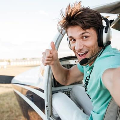 Male peering out of airplane giving a thumbs-up signal.